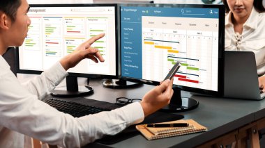 Projeyi koordine eden ve güncelleyen proje ekibi Gantt çizelge yazılımını kullanarak bilgisayarda program planladılar. Şirket işi için zaman ve süre belirleyen iş adamları. Önde.