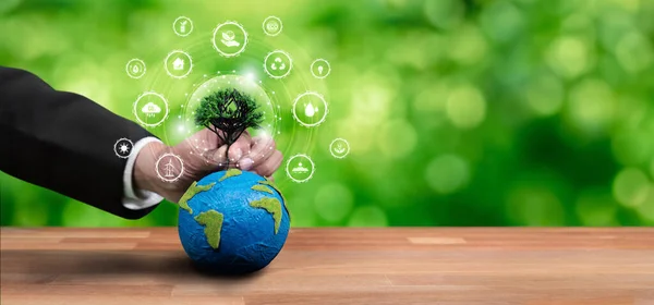 Businessman holding Earth with eco friendly icon design symbolize business company commitment to protect planet Earths ecosystem with net zero technology and ESG practice. Panorama Reliance
