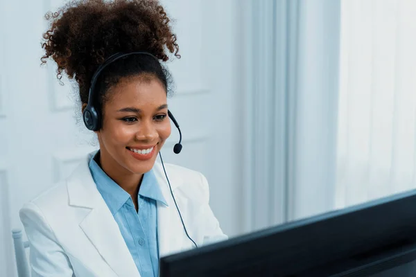 African American businesswoman wearing headset working in office to support remote crucial customer or colleague. Call center, telemarketing, customer support agent provide service on video call.