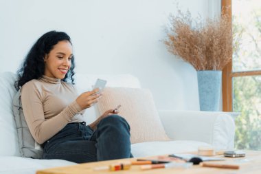 Genç mutlu bir kadın internetten alışveriş yaparak ürün satın alırken aynı zamanda internet üzerinden online kredi kartı ödeme sistemi ile çevrimiçi mağaza platformundan önemli siber güvenlik tarafından korunan ürünler sipariş ediyor.