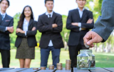 Businessman put coin to money saving glass jar on outdoor table with coin stack as sustainable money growth investment or eco-subsidize for corporate promoting environmental awareness. Gyre clipart