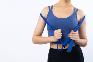 Spor giyim portresi giymiş enerjik bir kadın direnç sporu bandını geriyor. Genç atletik Asyalı kadın dayanıklılığı ve dayanıklılık eğitimi rutin konsepti tecrit edilmiş arka plan üzerine.