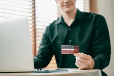 Genç adam internet bankacılığı için kredi kartlı dizüstü bilgisayar kullanıyor. İnternet üzerinden alışveriş yapıyor. Banka kartıyla modern ve kullanışlı online satın alma. Açılıyor
