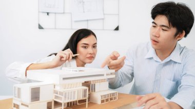 Closeup image of cooperate professional architect team working together by measuring house model on meeting table with architectural document and house model. Creative design concept. Immaculate. clipart