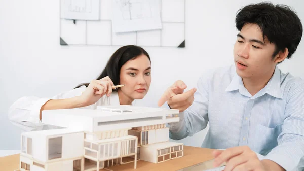 stock image Closeup image of cooperate professional architect team working together by measuring house model on meeting table with architectural document and house model. Creative design concept. Immaculate.