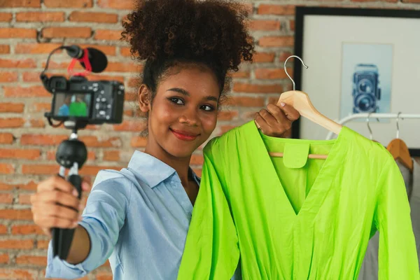 Woman influencer shoot live streaming vlog video review clothes crucial social media or blog. Happy young girl with apparel studio lighting for marketing recording session broadcasting online.