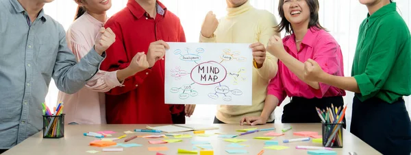 A cropped image of successful businesspeople presents new product marketing strategy using a mind map. Young creative business team brainstorm marketing idea together at modern office. Variegated.