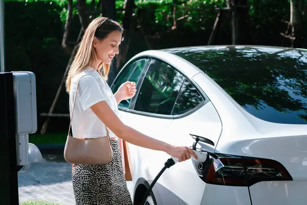 Junge Frau Fährt Sommer Mit Elektroauto Ladung Grünen Nachhaltigen Stadtgarten — Stockfoto