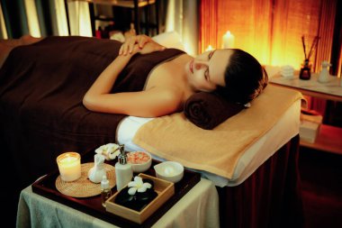 Beyaz kadın müşteri stres önleyici spa masajının keyfini çıkarıyor ve lüks otel ya da otelde sıcak mum ışığında güzellik teniyle eğleniyor. Sessiz.