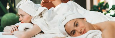 Beyaz havluyla beyaz bir spa yatağında dinlenen ve profesyonel bir masaj salonundaki masörle vücut masajı yapan birkaç güzel beyaz kadının portresi. Huzur..