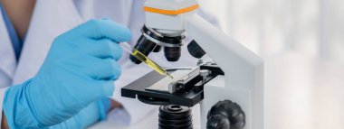 Laboratuvar araştırmacısı mikroskop kullanarak yeni ilaç ya da tedavi geliştirir. Laboratuvar mikrobiyoloji ekipmanları ile bilimsel uzmanlık ile sağlık hizmetlerinin teknolojik gelişimi. Panorama Katı