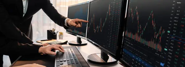 Group of traders discussing on office desk, monitoring stock market on monitor at office workplace. Businessman and broker analyzing stock graph together at stock trading company. Trailblazing