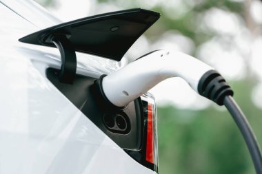 Temiz ve sürdürülebilir enerji kullanarak şarj olmak için EV şarj cihazına EV şarj cihazı takıldı. Doğal koruma ve çevre dostu araba yolculuğu konsepti. Yükselt