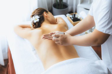 Masör elleri kadının sırtına aroma yağı döküyor. Masözler lüks otellerdeki kaplıca salonundaki müşteriler için yağ masajı prosedürü hazırlıyorlar. Aroma yağı vücut masajı konsepti. Sessiz.