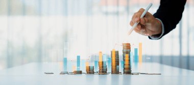 Dijital grafik göstergeli bozuk para yığını iş yatırımını ve ekonomik büyümeyi sembolize ediyor. Finansal hedefe ulaşmak ve kâr sağlamak için finansal planlama yapan bir iş adamı. Kurnaz.