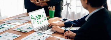 ESG 'nin çevresel sosyal yönetimi, çevre dostu şirket toplantılarında, temiz ve sürdürülebilir gelecekteki ekoloji için çevre korumasını uygulayan iş adamlarıyla dizüstü bilgisayarda sergileniyor. Önde.