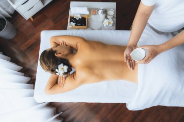Panorama üst manzara masörü elleri kadının sırtına aroma yağı döküyor. Masözler lüks otellerdeki kaplıca salonundaki müşteriler için yağ masajı prosedürü hazırlıyorlar. Aroma yağı vücut masajı konsepti. Sessiz.