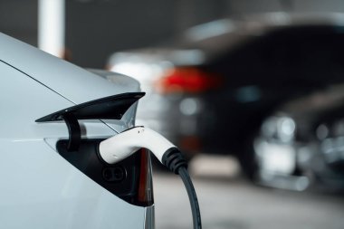 Alış veriş merkezinin otoparkında EV elektrikli araba şarjı şehir merkezindeki sürdürülebilirlik yaşam tarzını yeşil, temiz, yeniden şarj edilebilir elektrikli araç iç organları ile gösteriyor.
