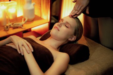 Beyaz kadın stres önleyici kafa masajı yapmaktan ve lüks otel veya otelde sıcak mum ışığında yüz güzelliği eğlencesi yapmaktan zevk alıyor. Sessiz.