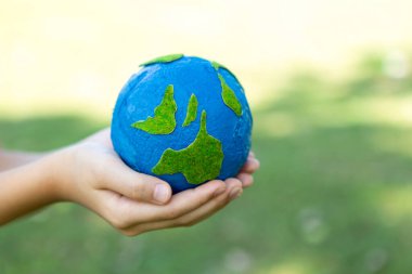 Dünya gezegenini ESG ilkesi ve çevre dostu enerjisiyle daha parlak bir gelecek için Dünya günü olarak el ele tutuşan genç çocuklar. Döngü