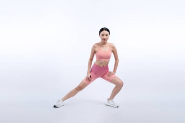 Spor giyimli çekici Asyalı kadın spor egzersizlerinden önce esneme hareketleri yapıyor. Stüdyo çekimlerinde ısınan atletik bir kadınla sağlıklı vücut bakımı egzersizi. Kuvvetli