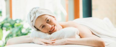 Güzel genç bir kadın, doğayla çevrili bir spa yatağında dinleniyor. Vücut masajına hazırım. Beyaz havluyla çekici bir kadın vücut masajı beklerken huzur içinde yatıyor. Kapatın. Huzur