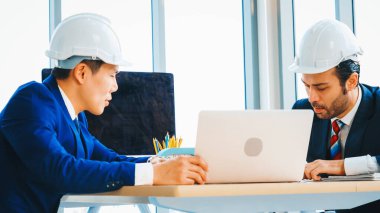 Mühendis ve mimar, mühendislik ve mimari proje planlaması hakkında ofis masasında toplanıyorlar. Jivy