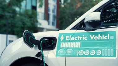 Elektrikli araba şarj istasyonunda EV şarj aleti ile elektrik yükleme istasyonunda dijital batarya durum hologram kablosu halka açık otoparkta görülüyor. Geleceğin yenilikçi her arabası ve enerji sürdürülebilirliği. İnceleyin