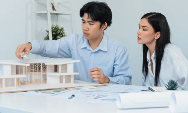 Kooperatif mühendis ekibinin portresi ev modelini ölçmek için cetvel ve mimari ekipmanlar kullanarak birlikte çalışıyor. Yaratıcı iş tasarımı ve takım çalışması konsepti. Tertemiz...