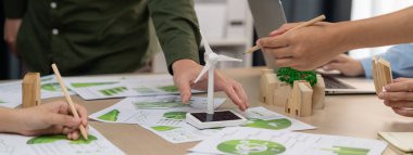 Yenilenebilir enerji ve eko kenti temsil eden ahşap bloğu temsil eden yel değirmeni modeli, çevreci dökümanların dağıtıldığı yeşil iş toplantısı masasına yerleştirildi. Ön manzara. Tanımlama.