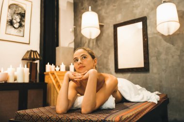 Beyaz havluyla beyaz kadın portresi kaplıca salonundaki rahat ve huzurlu sauna dolabının önündeki kaplıca yatağında yatıyor. Kapatın. Yan görüş. Huzur.