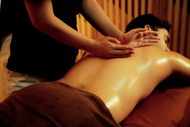 Beyaz erkek müşteri stres önleyici spa masajının keyfini çıkarıyor ve lüks otel ya da oteldeki ortam kaplıcalarında sıcak mum ışığında güzellik teniyle eğleniyor. Sessiz.