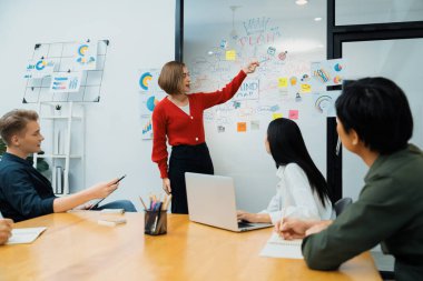 Profesyonel çekici kadın lider, modern iş toplantı odasında beyin fırtınası zihin haritalama istatistikleri ve renkli yapışkan notlar kullanarak yaratıcı pazarlama planını sunuyor. Tertemiz..