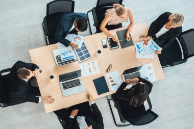 İş adamları grup toplantısı ofiste yukarıdan çekildi. İş kadınları, iş adamları ve ofis çalışanları toplantı masasında proje planlama belgeleriyle takım konferansında çalışıyorlar. Jivy