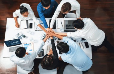 Üst düzey ofis çalışanları ofis odasında el ele tutuşarak iş sinerjisini ve iş yerindeki güçlü üretken takım çalışmasını sembolize ediyor. İş çalışanları arasındaki işbirliği ve birlik. Tedbirli