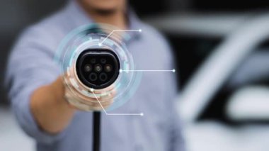 Kameranın önüne odaklanmış EV şarj cihazı fütüristik akıllı dijital EV batarya durum hologramını gösteriyor. EV araba şarjı sürdürülebilir güç için alternatif enerji kullanıyor. İnceleyin