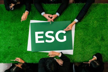 Çevre dostu sosyal yönetim kavramı olarak pazarlamayı planlayan çeşitli iş adamlarıyla yeşil çimen toplantı masasında panoramik afiş ESG sembolü. İlginç
