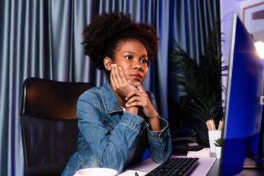 Genç Afrikalı yaratıcı ekran ekranına bakıyor, kot gömlek giyiyor. Projeyi düşünmek ya da işyerinde yeni teknoloji okumak. İş planlama uzmanı konsepti. Tatlandırıcı.