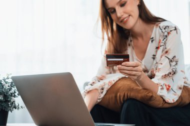 Genç mutlu kadın internetten alışveriş yaparak ürün satın alırken aynı zamanda internet üzerinden online ödeme sistemi ile çevrimiçi mağaza platformundan en yüksek siber güvenlik tarafından korunan ürünler sipariş ediyor.