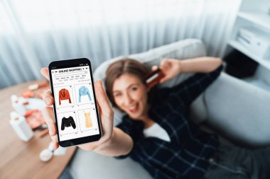 Genç mutlu kadın internetten alışveriş yaparak ürün satın alırken aynı zamanda internet üzerinden online ödeme sistemi ile çevrimiçi mağaza platformundan en yüksek siber güvenlik tarafından korunan ürünler sipariş ediyor.