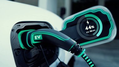 Ev şarj istasyonundaki EV şarj aleti fişe takılı ve dijital akü durum hologramını gösteren elektrikli arabayı şarj ediyor. Akıllı ve fütüristik ev enerjisi altyapısı. İnceleyin
