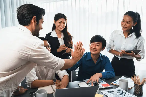 Diverse group of office employee worker high five after making agreement on strategic business marketing planning. Teamwork and positive attitude create productive and supportive workplace. Prudent