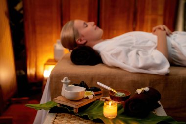 Aromaterapi masajı ambiyansı ya da spa salonu kompozisyon düzeneği bulanık kadınlara odaklı dekor mumları ve spa aksesuarları ile tatil köyü veya otel arka planında keyifli aroma spa masajı yapan. Sessiz.