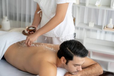 Lüks spa salonunda sıcak mum ışığı atmosferi olan lüks kaplıcalarda deri dökme tedavisi gören mutlu bir adam. Sağlık kaplıcasında güzellik tedavisiyle tuz temizliği. Sessiz.