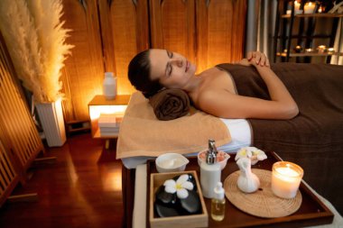 Beyaz kadın müşteri stres önleyici spa masajının keyfini çıkarıyor ve lüks otel ya da otelde sıcak mum ışığında güzellik teniyle eğleniyor. Sessiz.