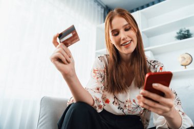 Genç mutlu kadın internetten alışveriş yaparak ürün satın alırken aynı zamanda internet üzerinden online ödeme sistemi ile çevrimiçi mağaza platformundan en yüksek siber güvenlik tarafından korunan ürünler sipariş ediyor.