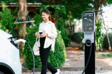 Genç kadın ve sürdürülebilir kentsel yol, bahar bahçesi, yeşil şehir sürdürülebilirliği ve çevre dostu EV arabadaki açık kafede çalışan EV elektrikli araba. Yararlı