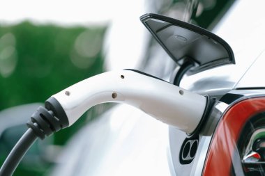 Elektrikli araç portuna bağlı EV şarj prizi kolu şarj istasyonundan şarj oluyor. Modern tasarlanmış EV araba ve daha iyi bir gelecek konsepti için temiz enerji sürdürülebilirliği. Eşzamanlama