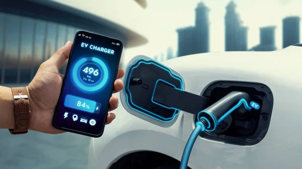 EV car battery status on EV smartphone application while recharge battery from public city charging station. Innovative technological advancement of EV car and alternative energy utilization. Peruse