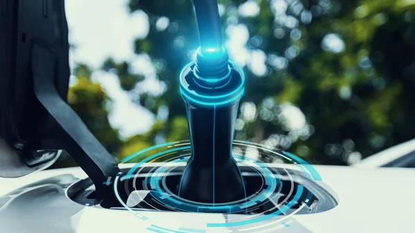 Closeup EV charger plug into electric car for electric recharge by electric charging station with glow light hologram on charger. Cutting-Edge innovation of green future energy sustainability.Peruse